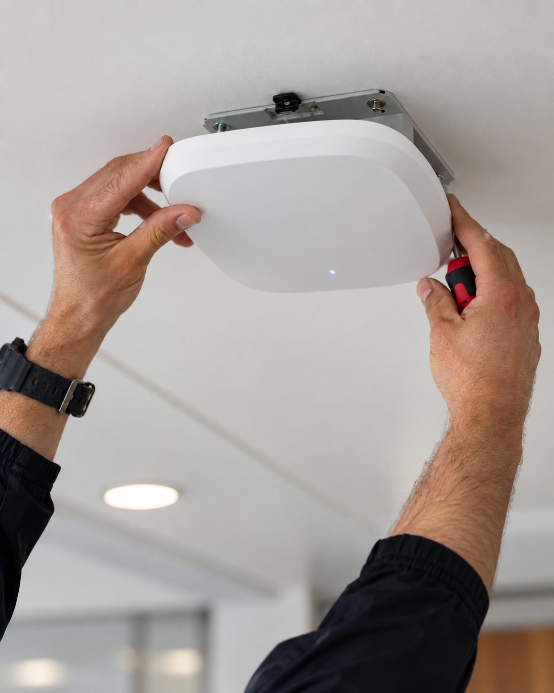 Engineer installing a ceiling-mounted wireless access point in a care home
